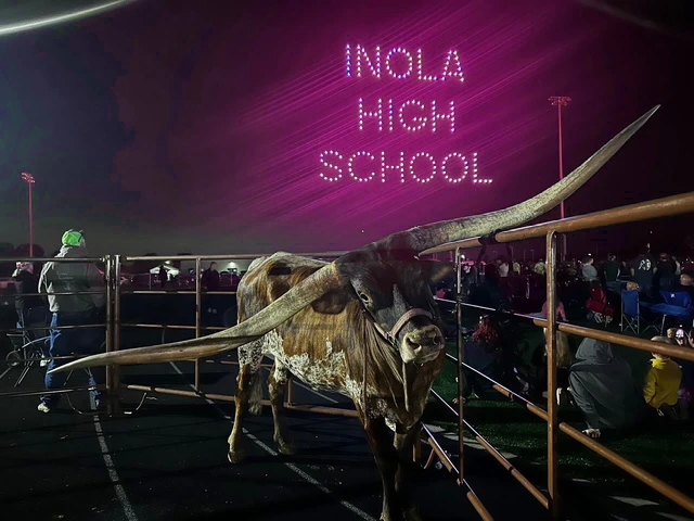 Longhorn steer in a pen as a drone show spells Inola High School for T-Mobile 5G Lights