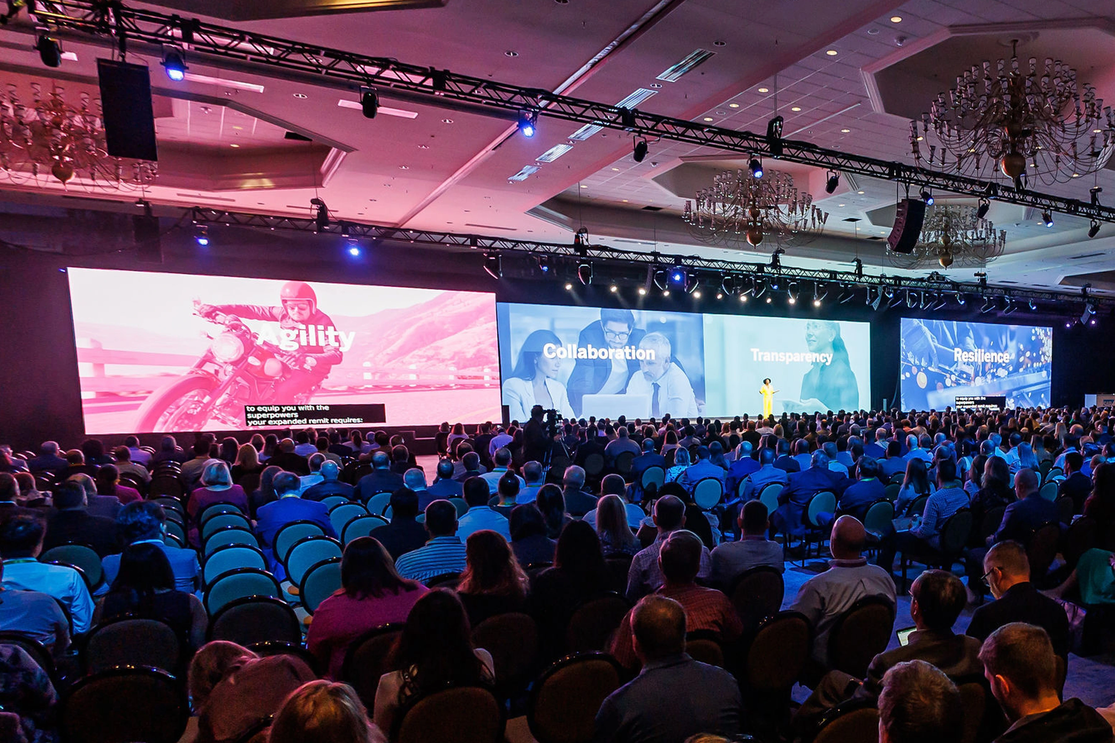 Speaker in yellow at SAP Spend Connect Live before Agility, Collaboration, Transparency and Resilience screens