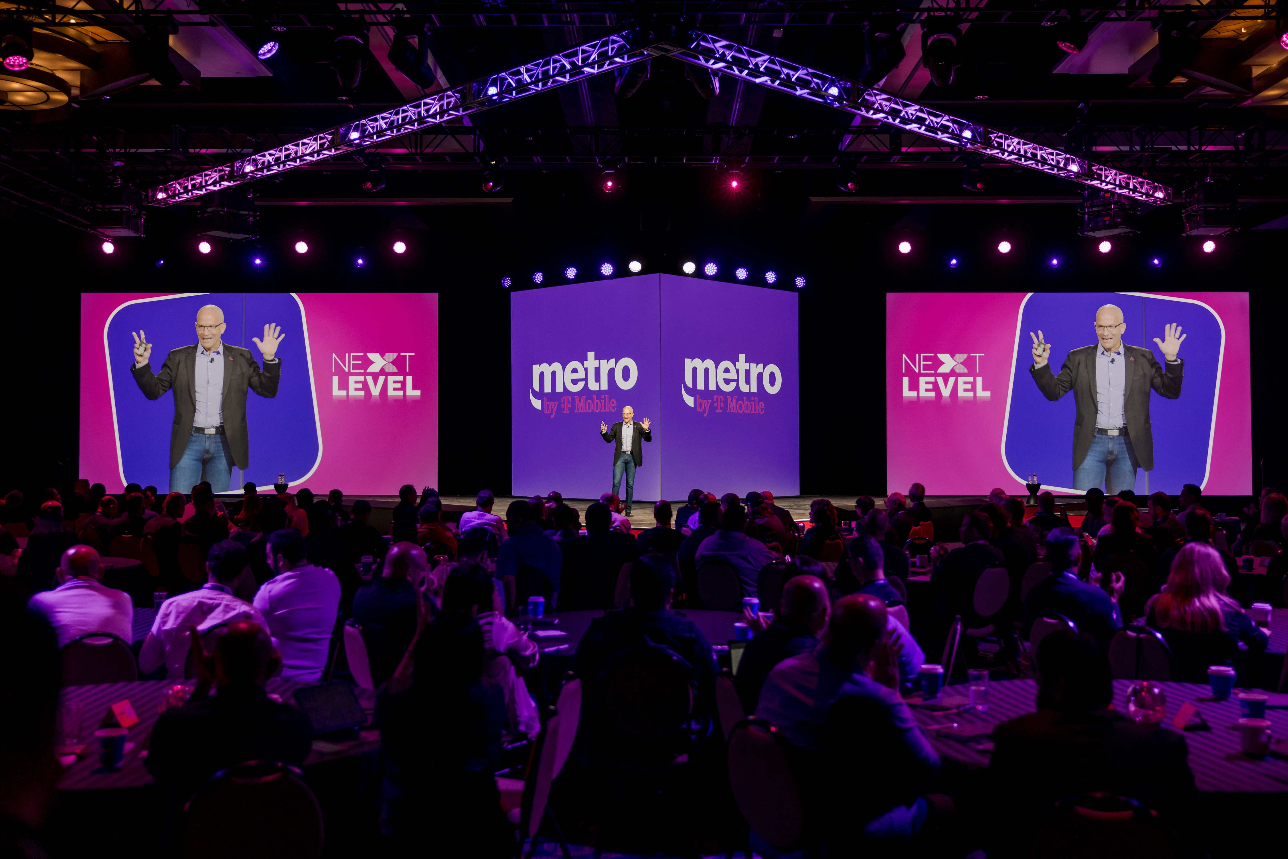 Metro by T-Mobile Next Level keynote with the speaker mirrored on three giant screens