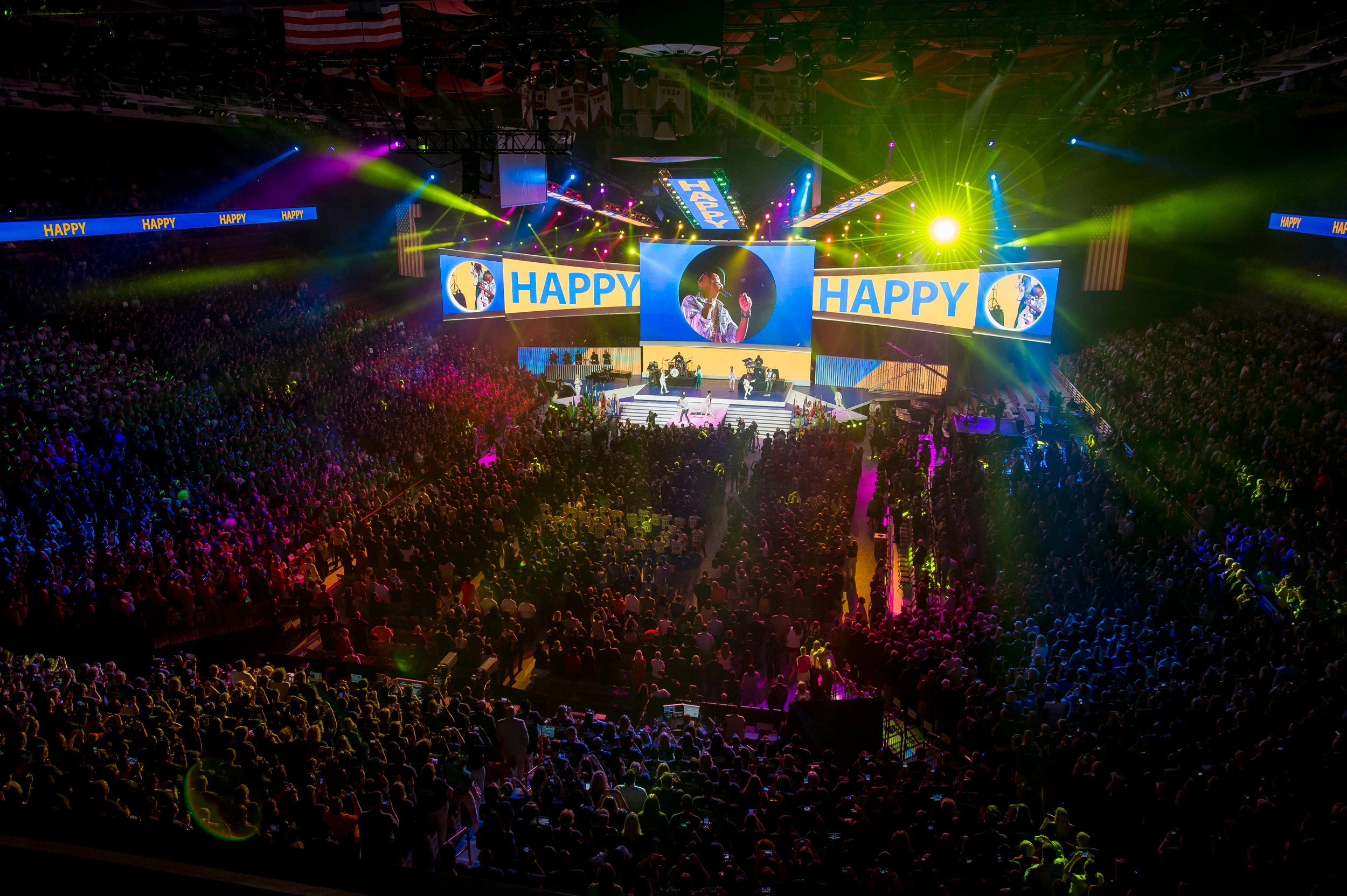 Packed arena at Walmart Shareholders 2014 as Pharrell Williams performs Happy under sweeping lights