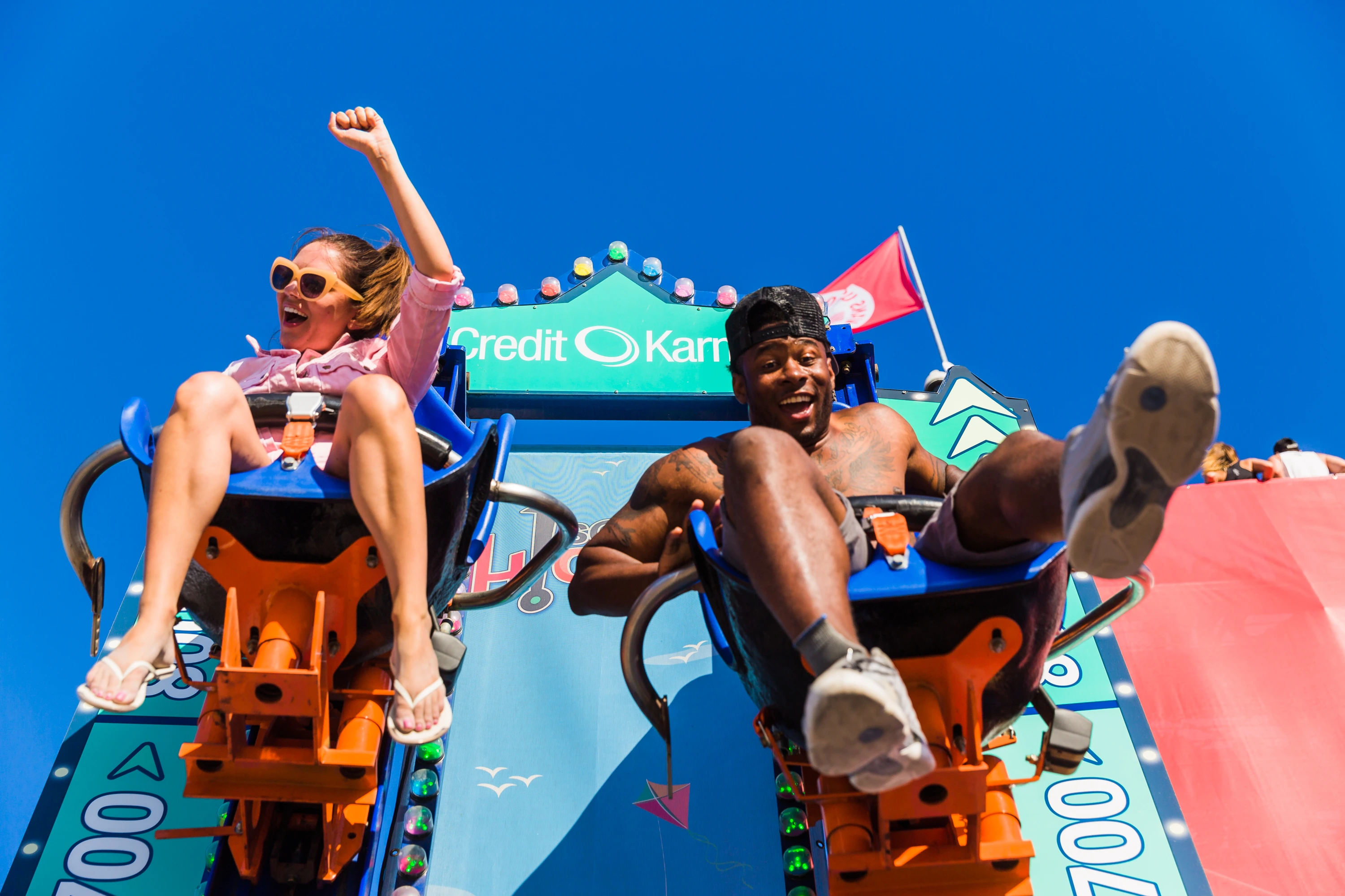 Riders drop down the Credit Karma Score Higher tower ride against a blue sky