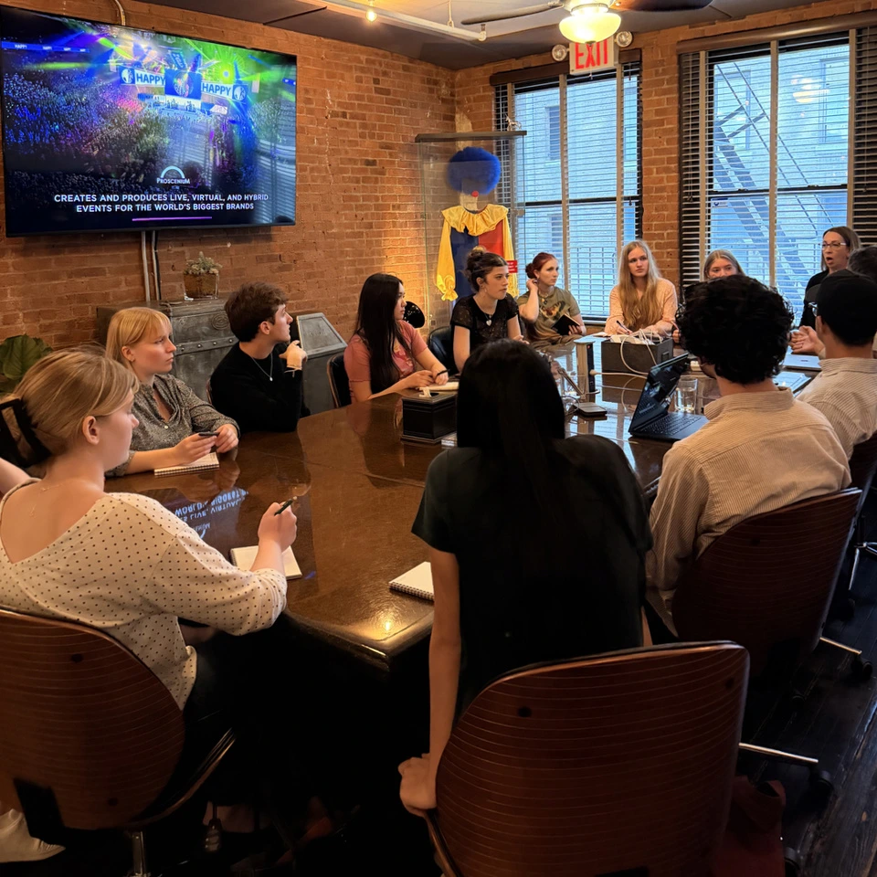 Syracuse design students around the Proscenium conference table watching an agency showreel